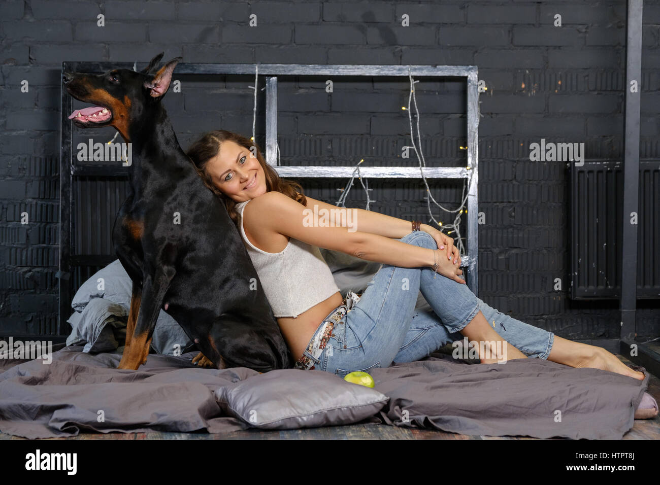 Joven mujer bonita con negro doberman perro en la cama Fotografía de stock  - Alamy