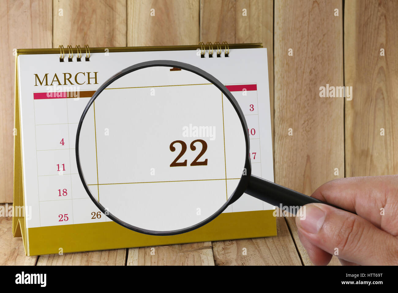 Lupa en mano en el calendario puede mirar a veintidós días del mes,Focus Número veintidós en marzo,Concepto de negocios y reuniones. Foto de stock