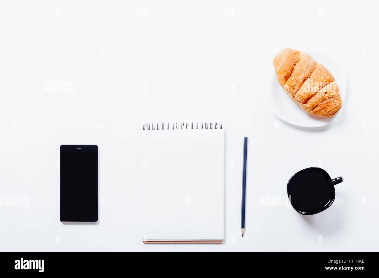 Croissant, café, auriculares, teléfono móvil y portátil en blanco tabla, vista superior Foto de stock