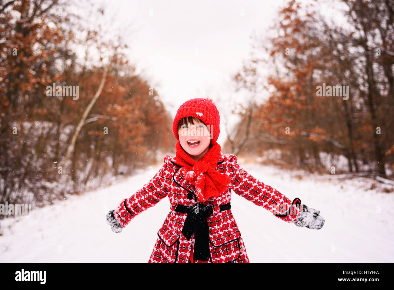 Chica en invierno bosque permanente con los brazos extendidos Foto de stock