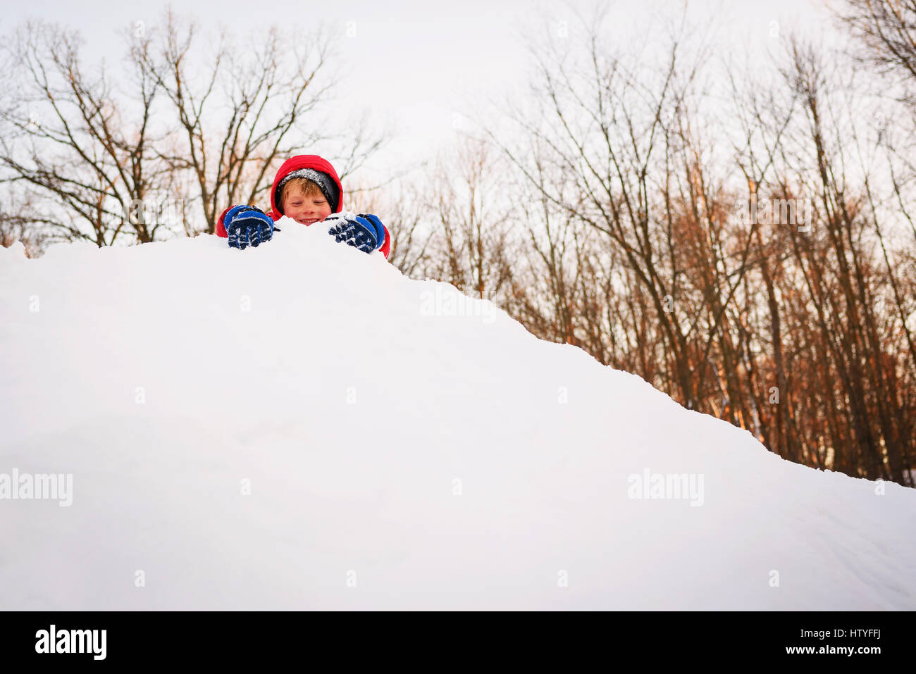 Niño jugando en la cima de un montón de nieve Foto de stock