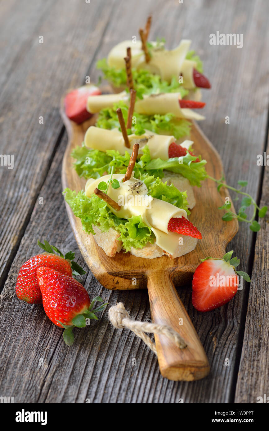 Canapés con deliciosos panes de queso y fresas en pan ciabatta italiana con hojas de lechuga Foto de stock