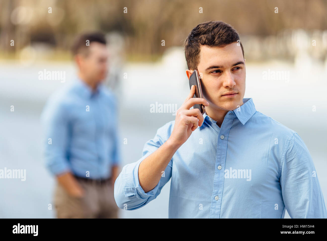 Empresario hablando a su teléfono con un amigo en el fondo desenfocado Foto de stock