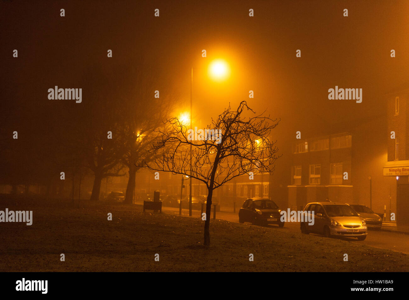 Amarillo-ámbar resplandor de vapor de sodio luces de calle en una noche brumosa, Queensbury, Harrow, noroeste de Londres, Inglaterra, HA8 5NP, REINO UNIDO. Foto de stock