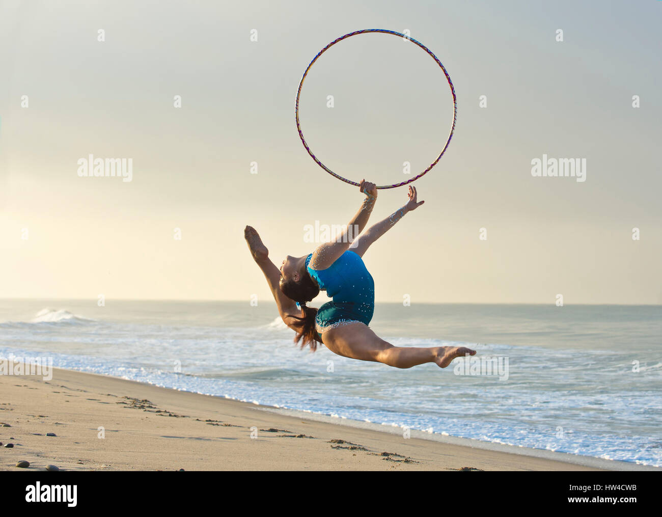 Gimnasta caucásica saltando con aro en la playa Foto de stock
