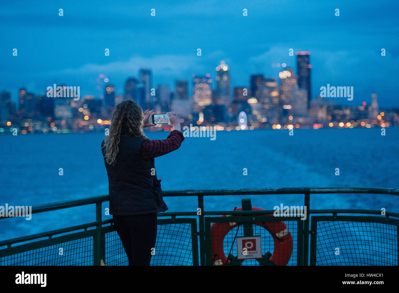 Mujer caucásica en barco fotografiar waterfront urbano con teléfono celular Foto de stock