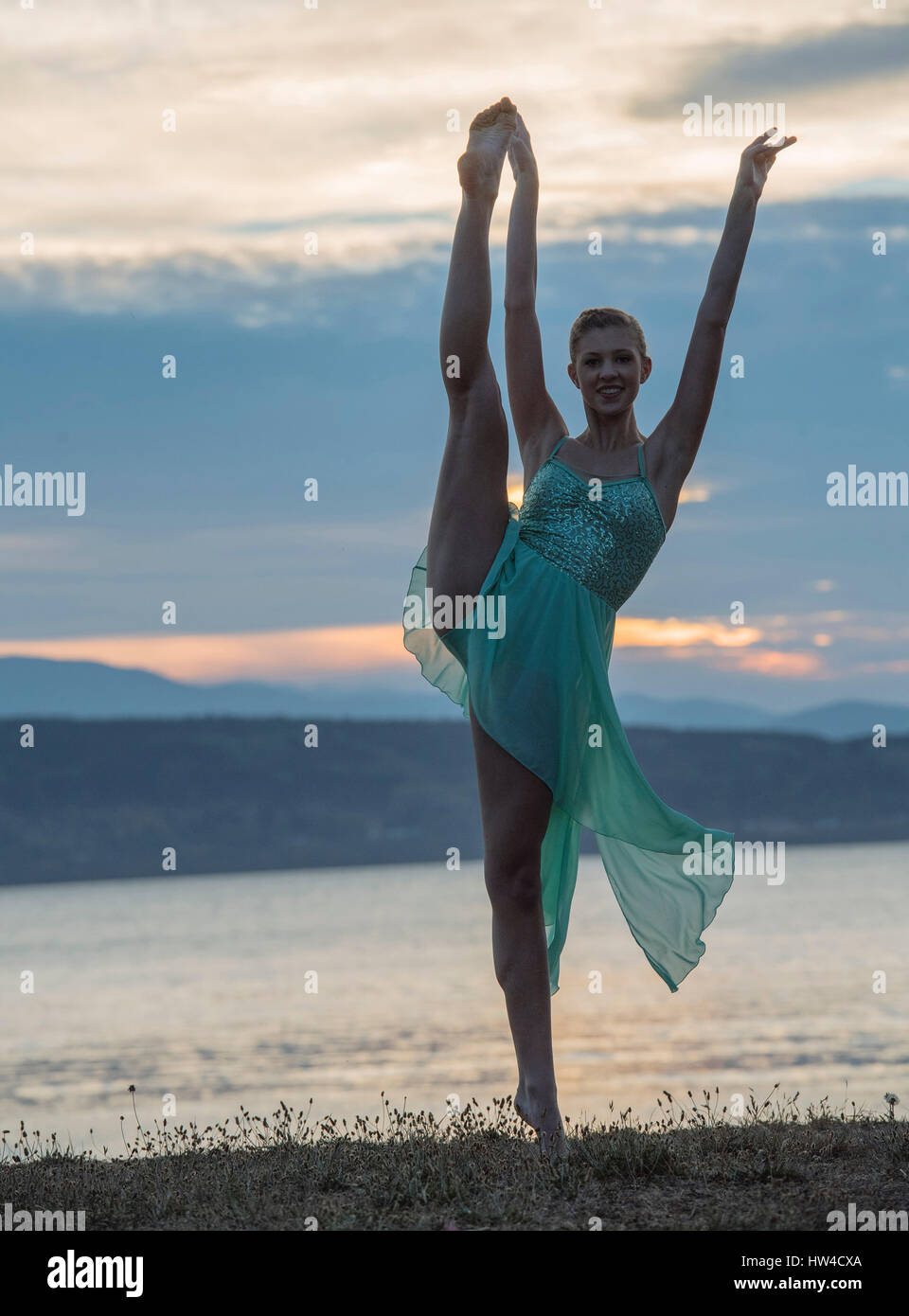 Bailarina caucásica bailando en playa en el atardecer. Foto de stock