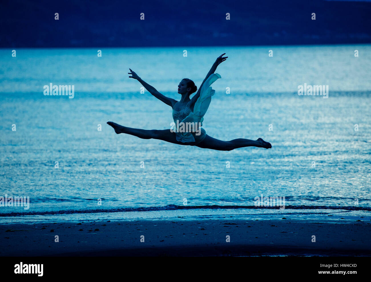 Bailarina caucásica saltando sobre la playa en el atardecer. Foto de stock