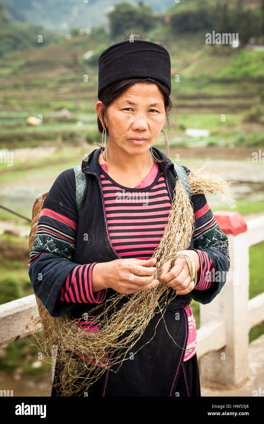 Lao Cai, SAPA, Vietnam - 5 de mayo de 2014: el retrato de mujer Hmong tribales en las ropas de pie en la calle, cerca de los campos de arroz con heno en la HA. Foto de stock
