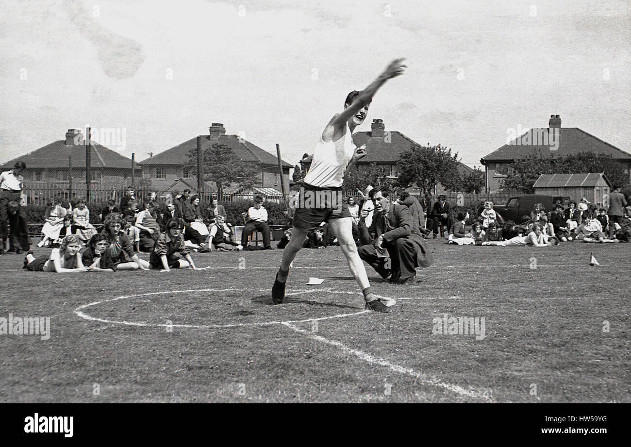 1940, el colegial arroja el discus en una jornada deportiva escolar, Inglaterra. Foto de stock