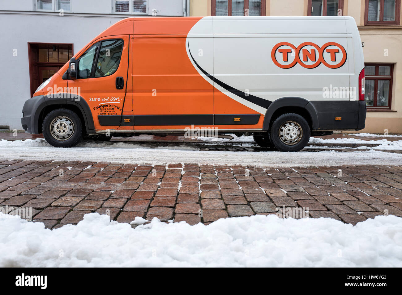 TNT Express delivery van sobre una calle cubierta de nieve parcialmente Foto de stock