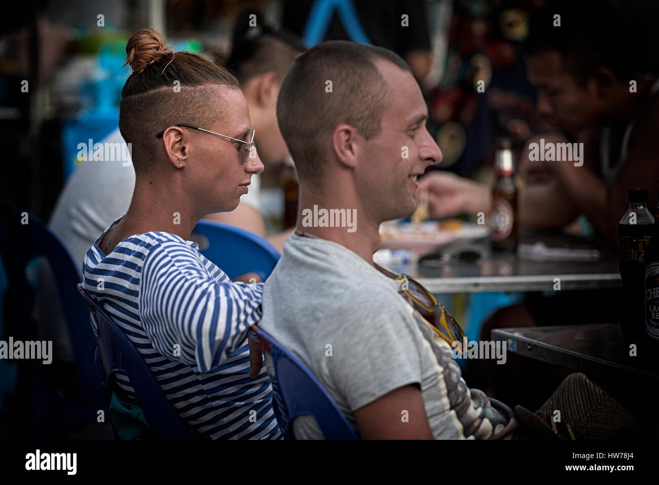 Mujer con peinado Top Knot y parte de la cabeza afeitada junto a su  compañero de aspecto masculino Fotografía de stock - Alamy