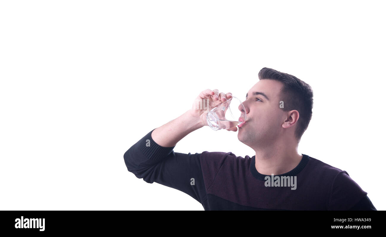 Joven de beber agua de un vaso fondo blanco. Foto de stock