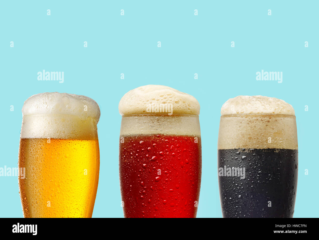 La luz roja, y los vasos de cerveza oscura sobre fondo azul. Foto de stock