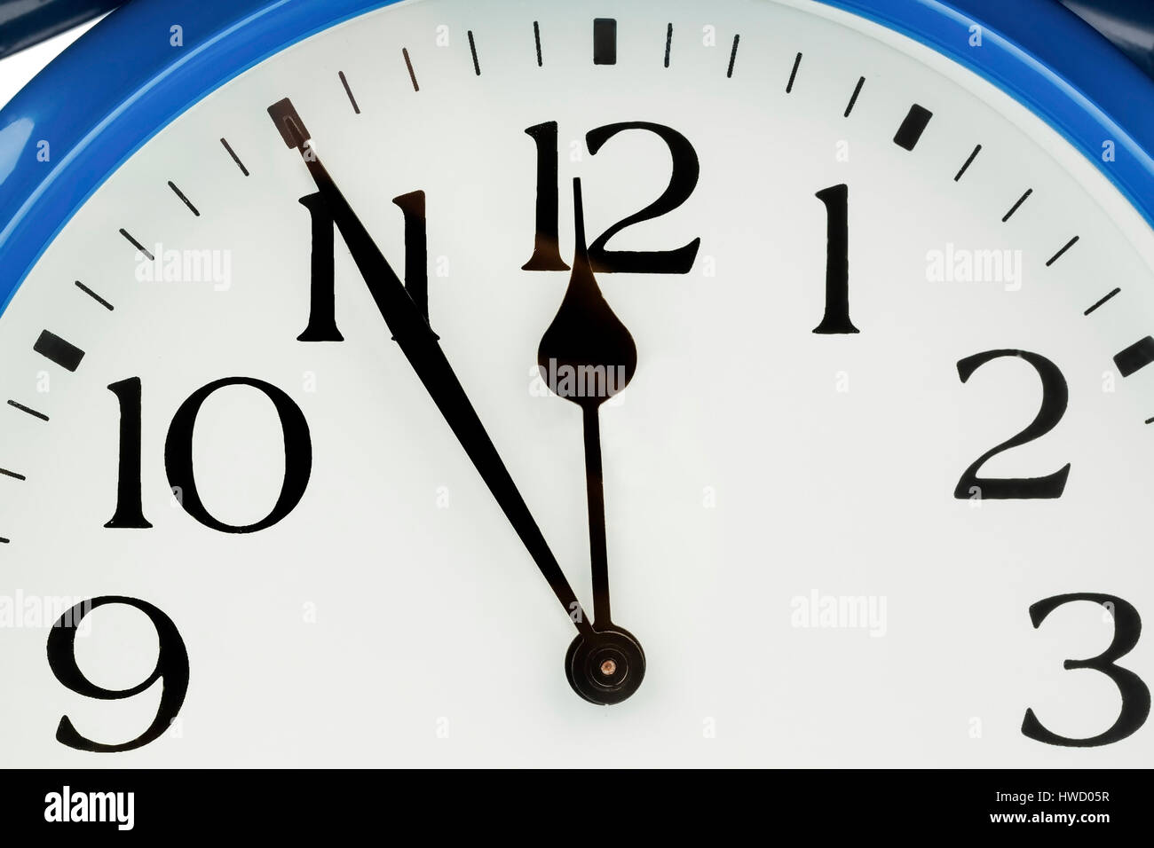 Un reloj de alarma azul indica 5 antes 12., Ein blauer Wecker zeigt 5 vor 12 un. Foto de stock