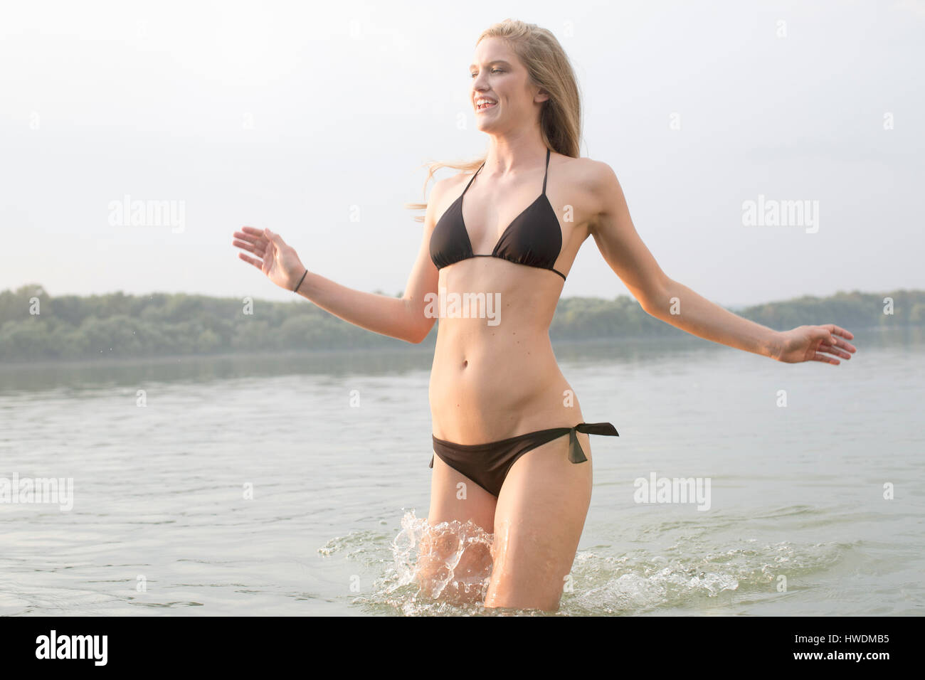 Mujer en bikini salpicaduras en el río. Foto de stock
