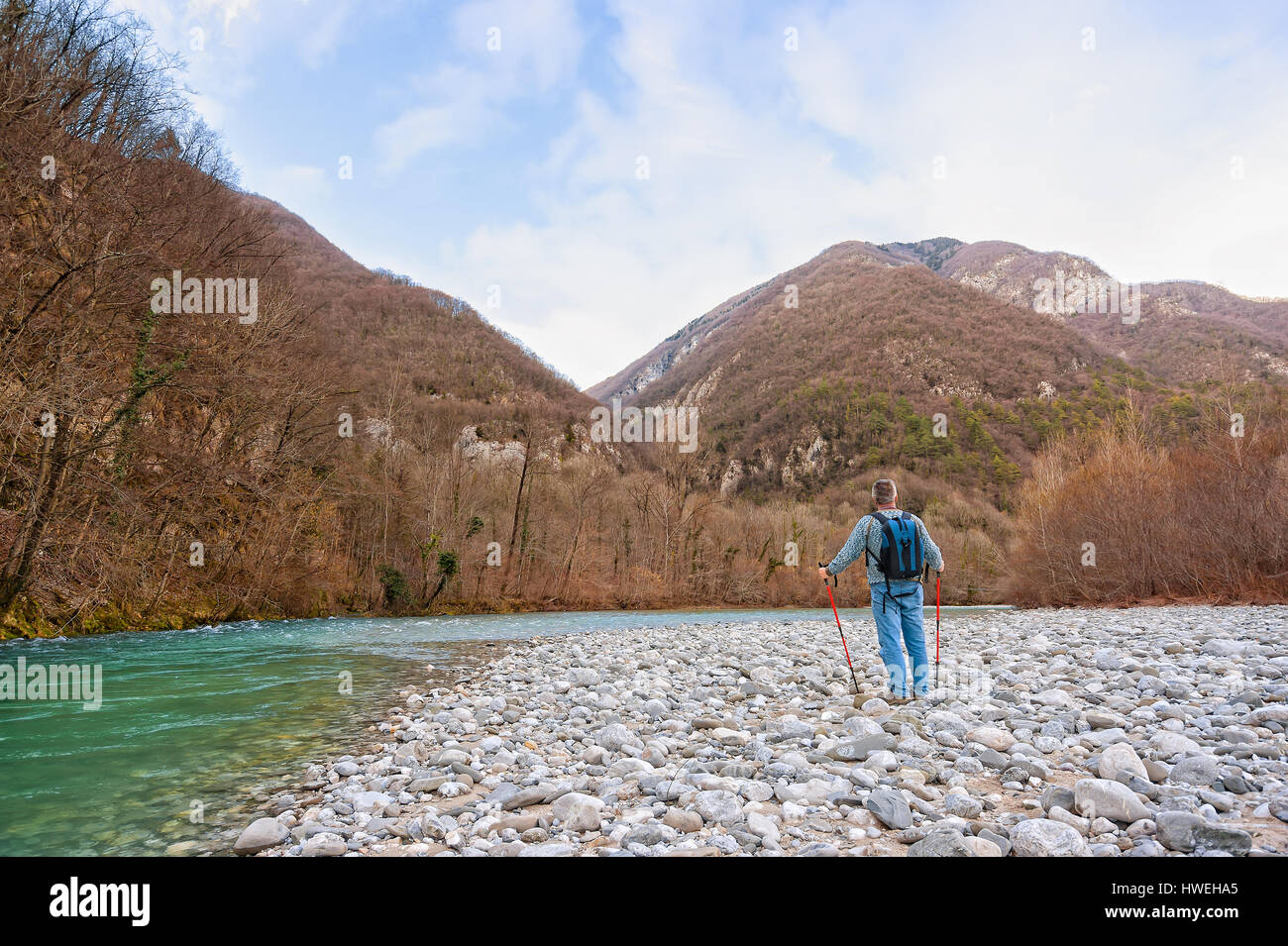 Caminante en la orilla de un río. Trekking hacia la montaña. Rambler de alrededor de 60 años de edad. Foto de stock