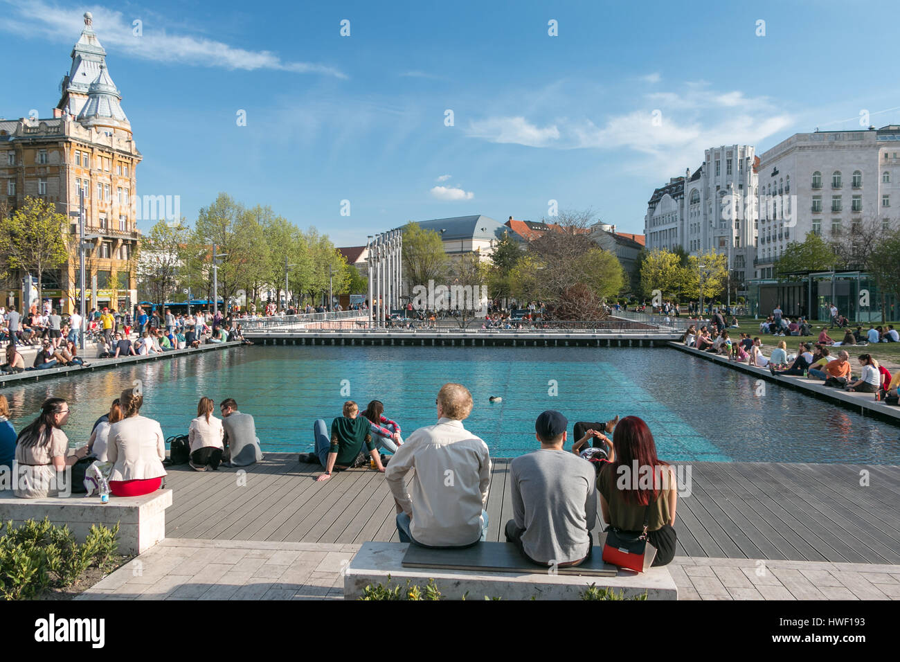 La gente se sentaba afuera en una piscina reflectante en Erzsebet ter en Budapest en la primavera Foto de stock