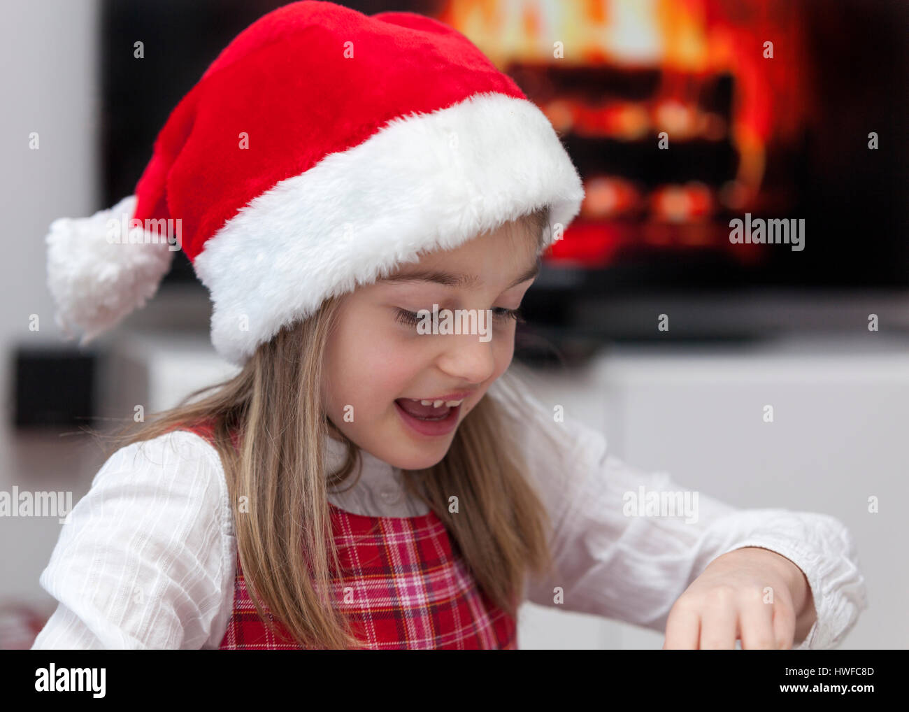 Happy cute emocionado joven abriendo regalos de Navidad en frente de la  chimenea vistiendo un gorro de Papá Noel de Navidad modelo de liberación:  Sí. Liberación de propiedad: No Fotografía de stock -