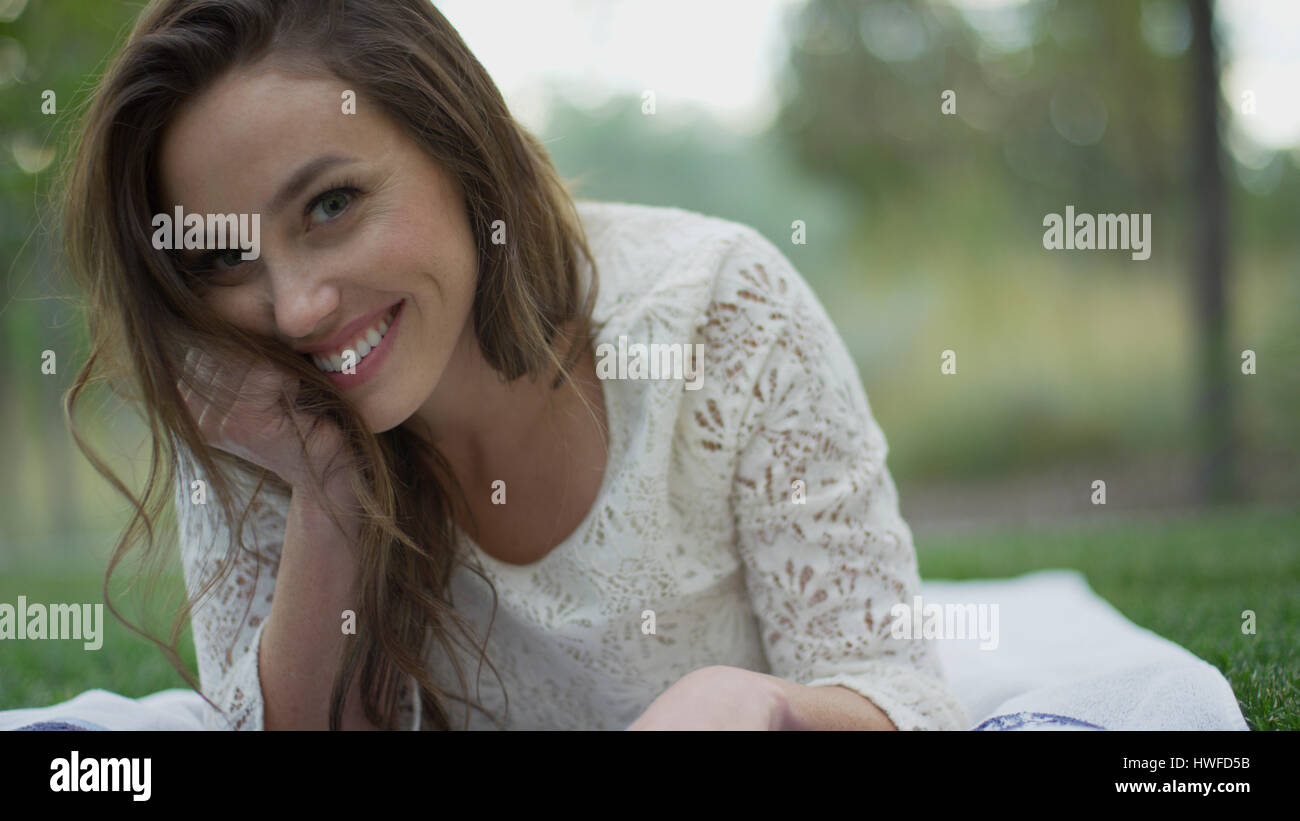 Close Up retrato de mujer sonriente sentar en la hierba Foto de stock