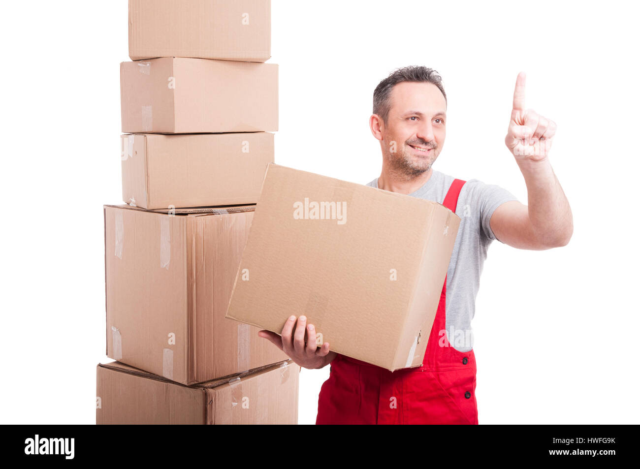 El transportador guy sosteniendo la caja de cartón mediante pantalla táctil invisible y sonriente aislado sobre fondo blanco con espacio de texto Copiar Foto de stock