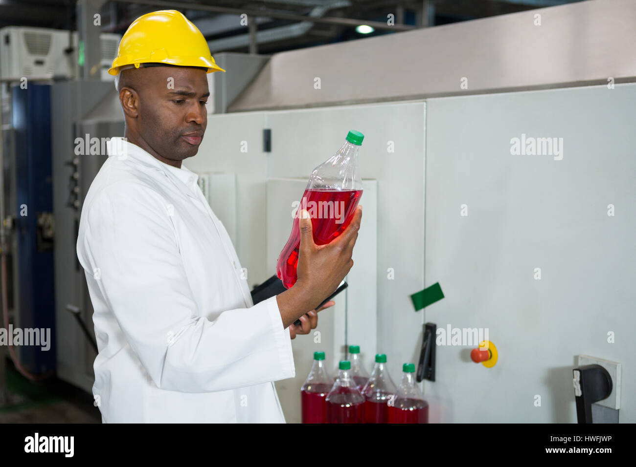 Trabajador serio examen de botellas en la fábrica de jugo Foto de stock