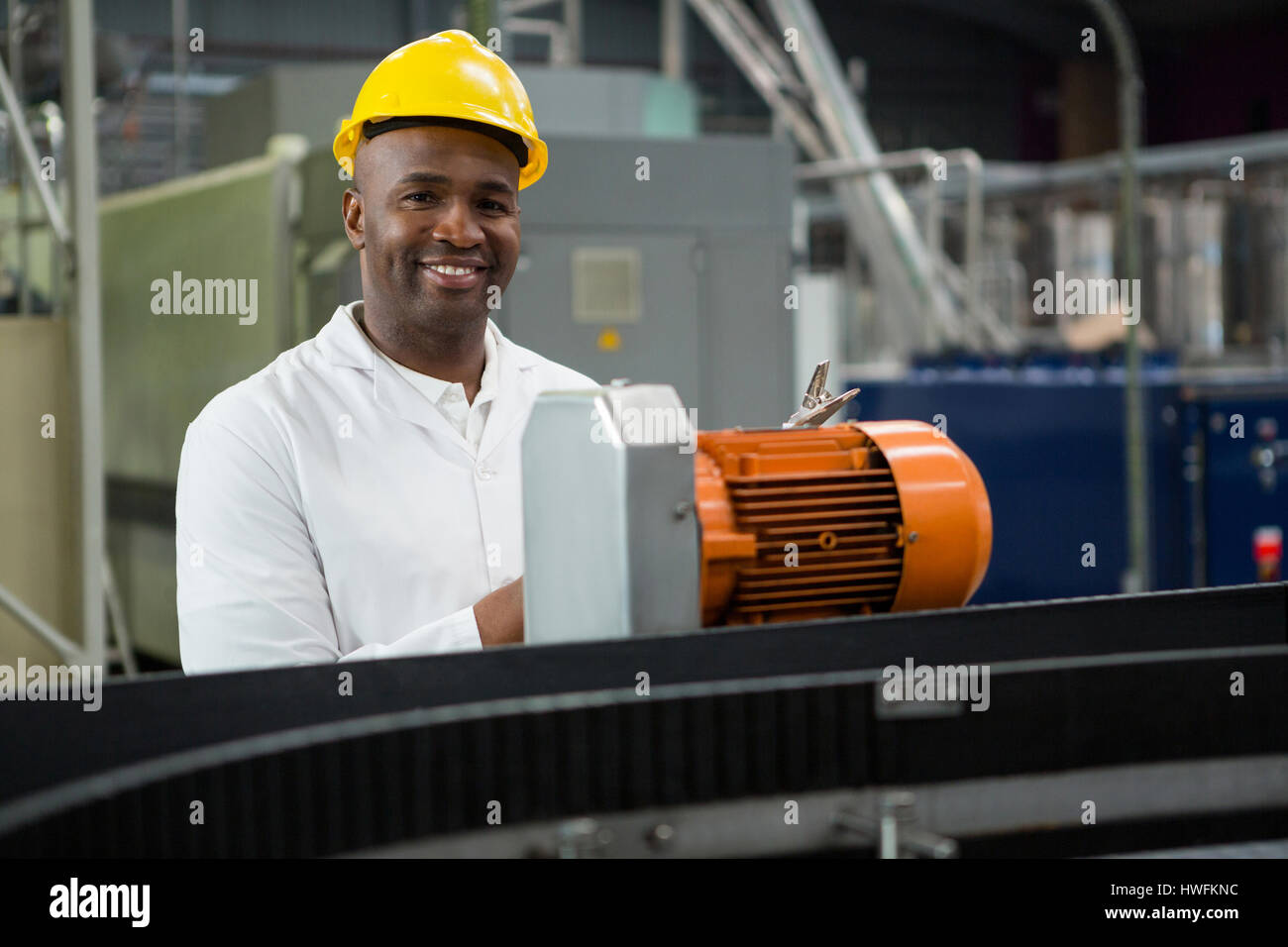Retrato del ingeniero sonriendo inspeccionando las máquinas en la fábrica de jugo Foto de stock