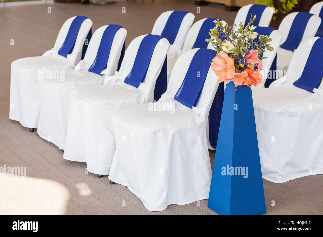 Hermosamente decorado con telas blancas y azules y flores sillas Foto de stock