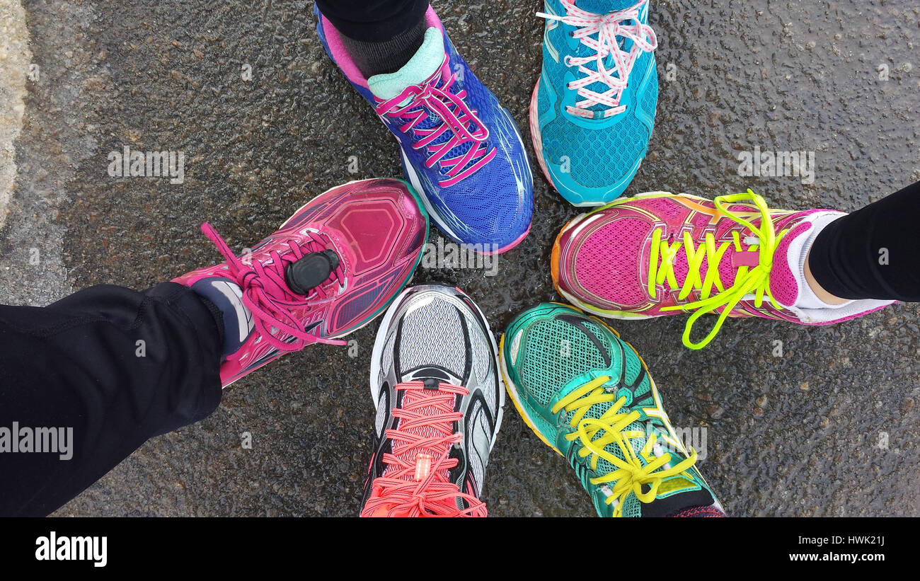 Vista aérea de coloridos zapatos para correr corredores' pies. Pavimento mojado, un corredor vistiendo un pod de pie para un podómetro Fotografía de stock - Alamy
