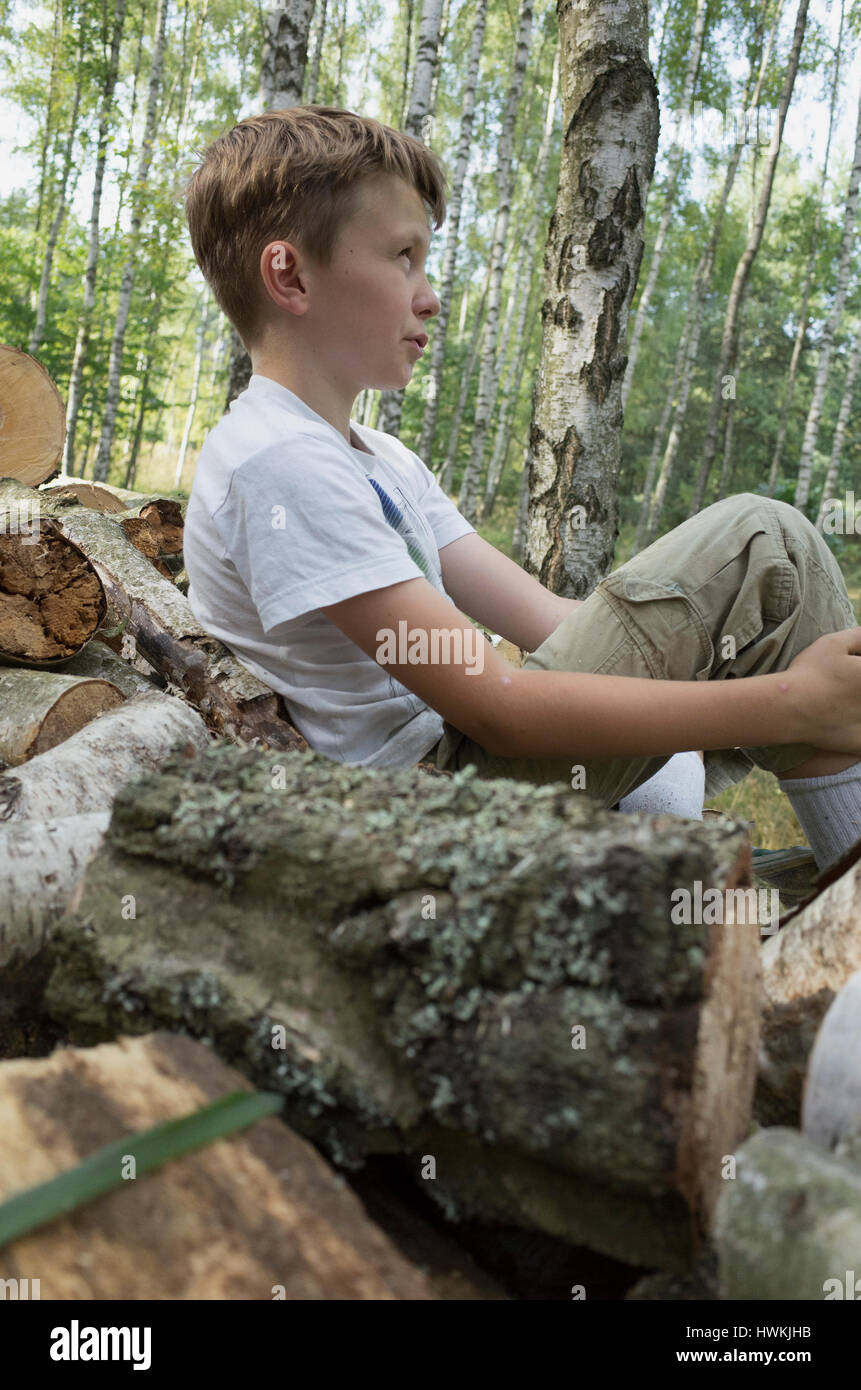 Muchacho descansando sobre el montón de leña los registros de pila que él ayudó a la edad de 10 años. Zawady Polonia Central Europa Foto de stock