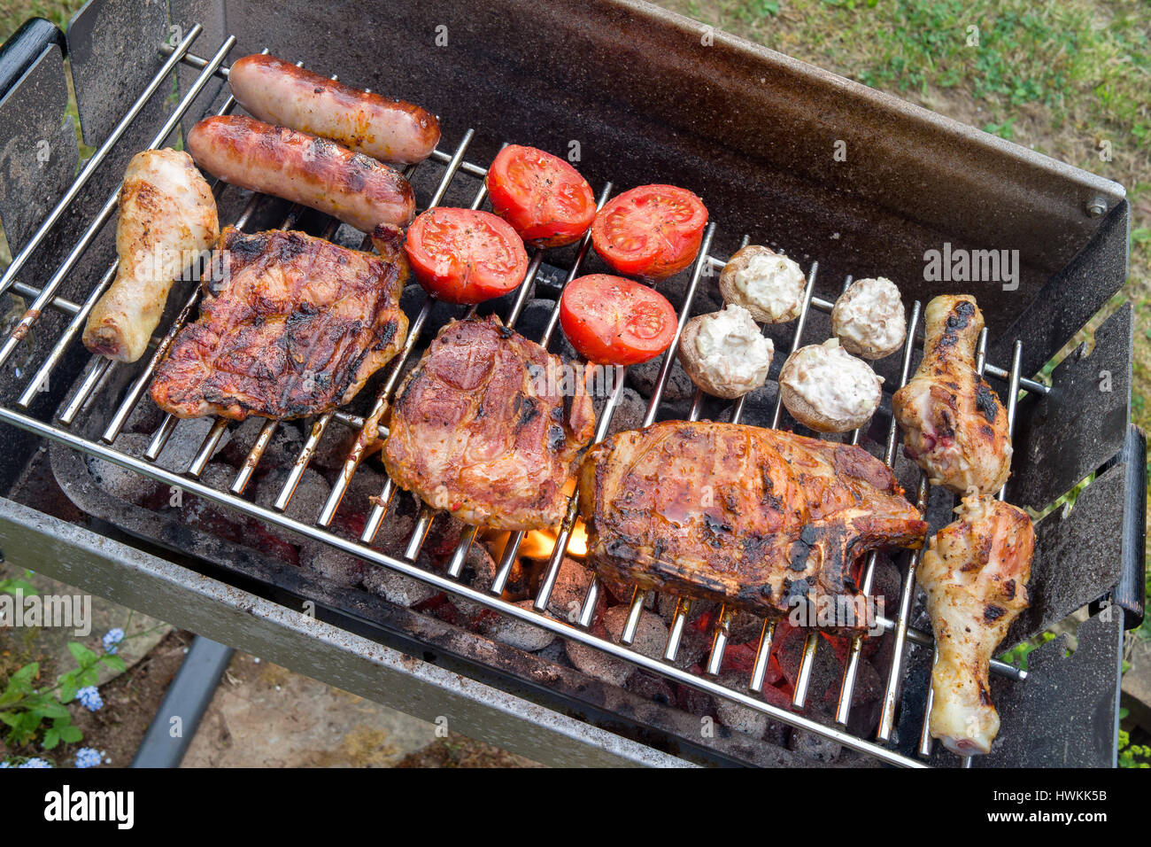 Diferentes carnes y vegetales en la parrilla con carbón Foto de stock