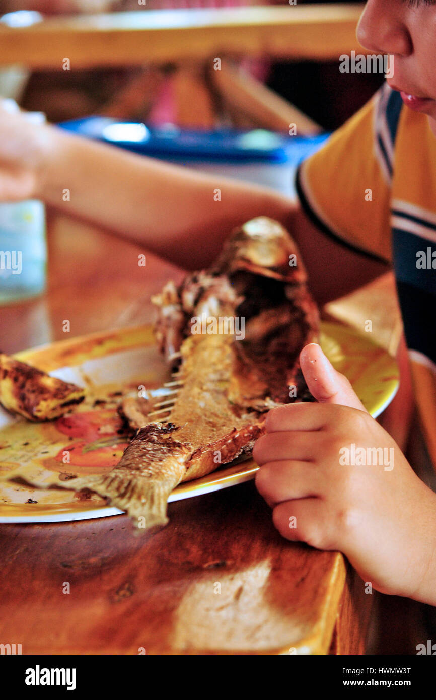 Un niño come frito (chelon mullet) en El Morro puerto. Provincia de