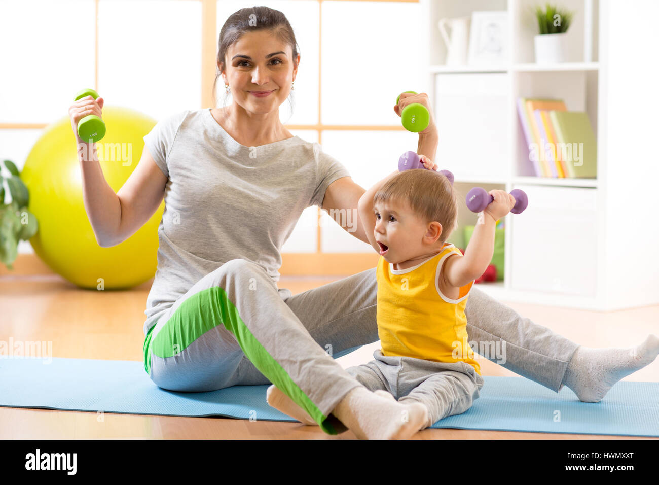 La madre con el bebé haciendo gimnasia y ejercicios físicos Foto de stock