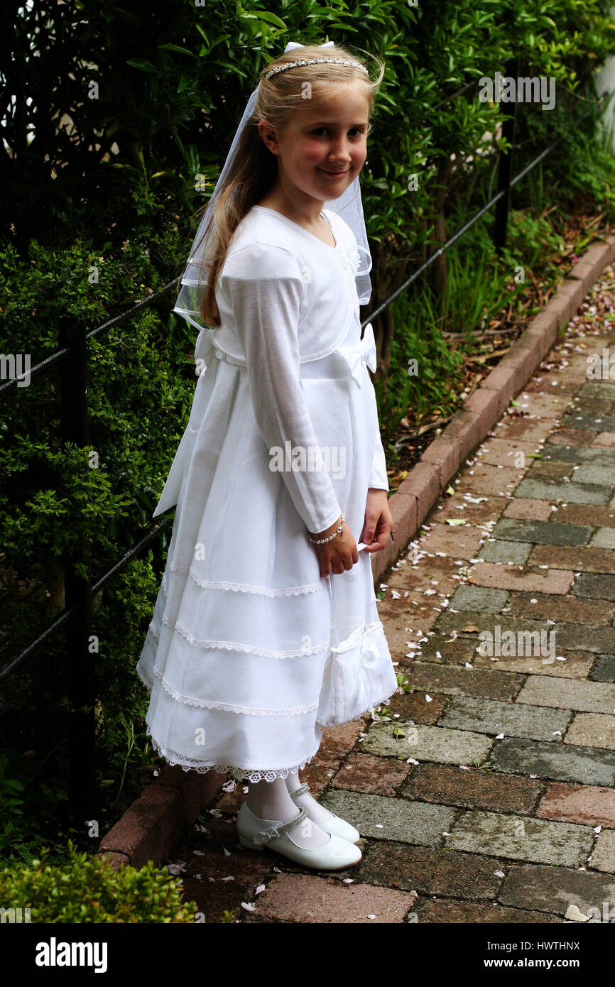 La primera Comunión la niña de pie en el jardín vestida con su vestido  blanco y velo Fotografía de stock - Alamy
