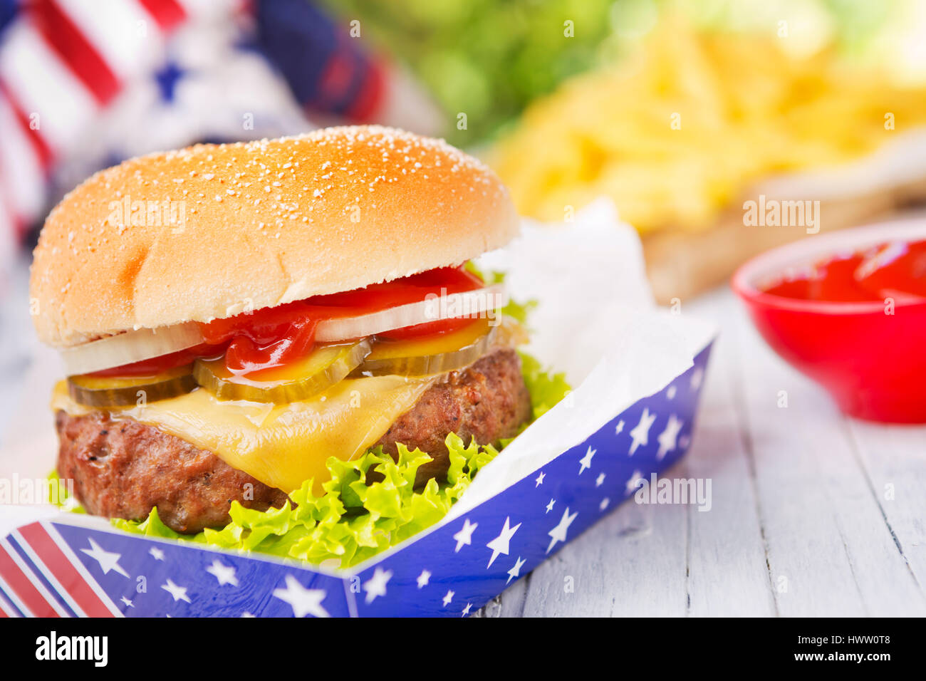 Una sabrosa hamburguesa con papas fritas en una mesa al aire libre. Foto de stock