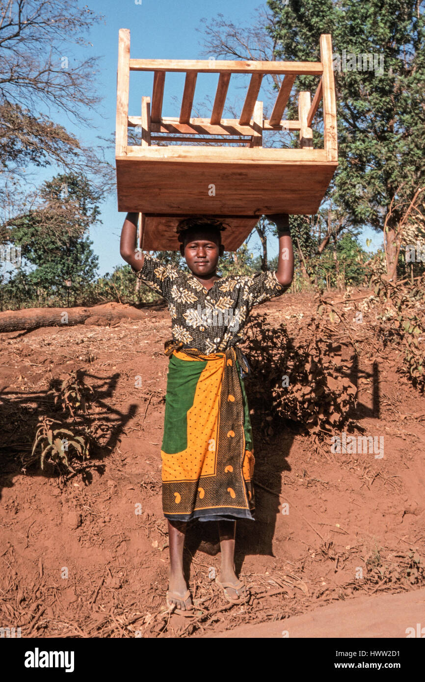 Una niña transporta muebles hechos a mano y sobre su cabeza, moshi Kilimanjaro, Tanzania Foto de stock