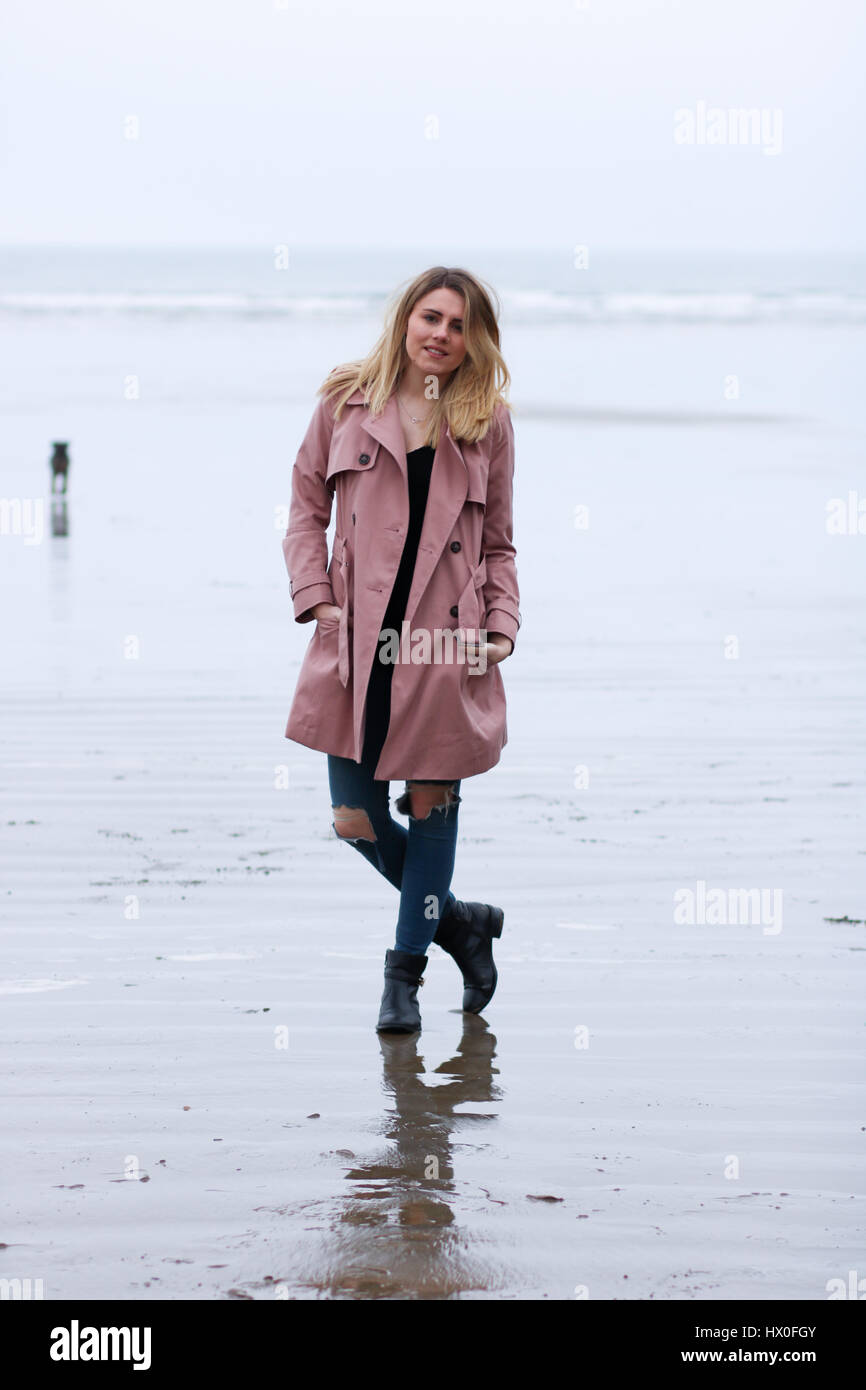 Joven rubia mujer vistiendo abrigo rosa en Black Rock Sands Beach Foto de stock