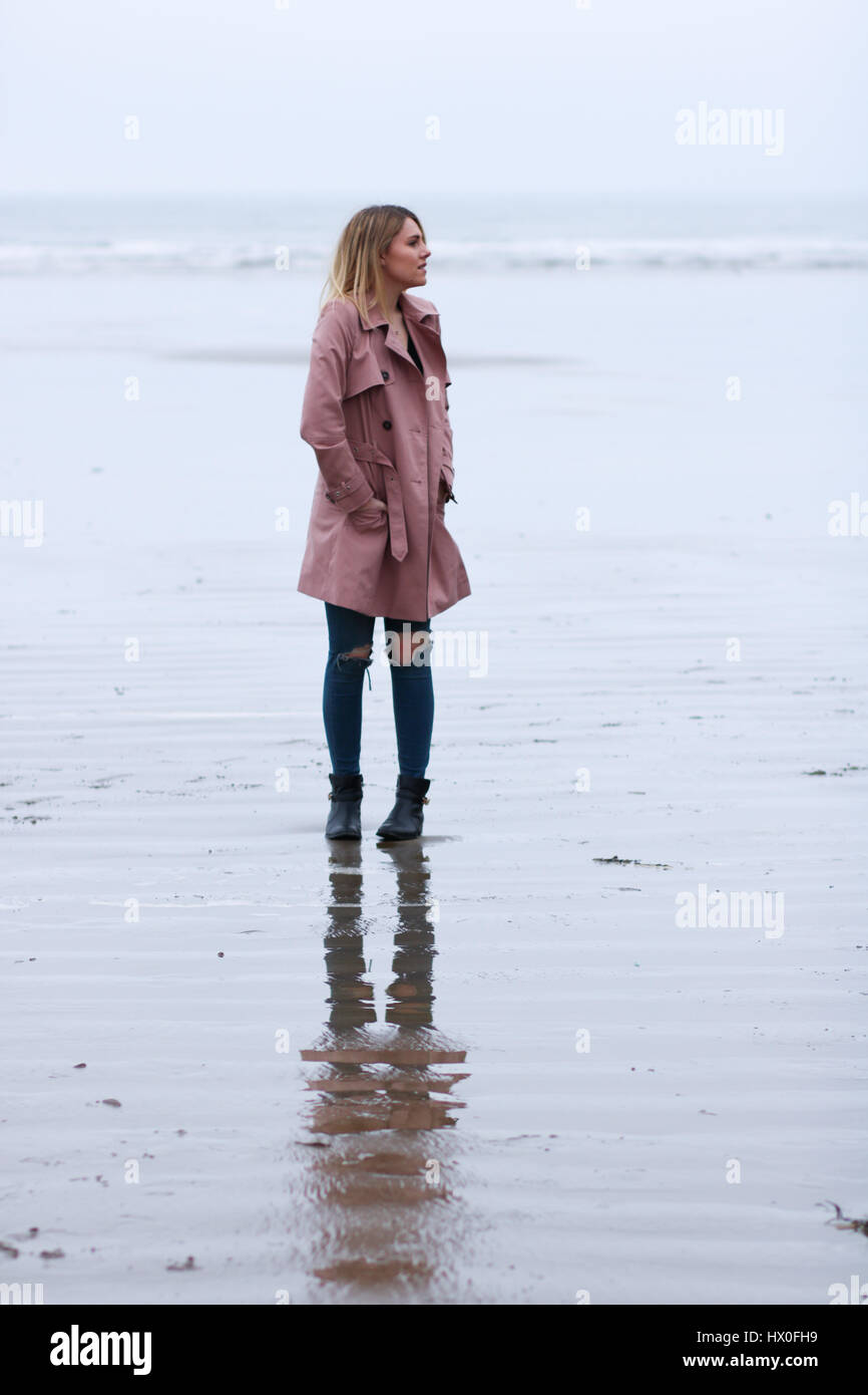 Joven rubia mujer vistiendo abrigo rosa en Black Rock Sands Beach Foto de stock