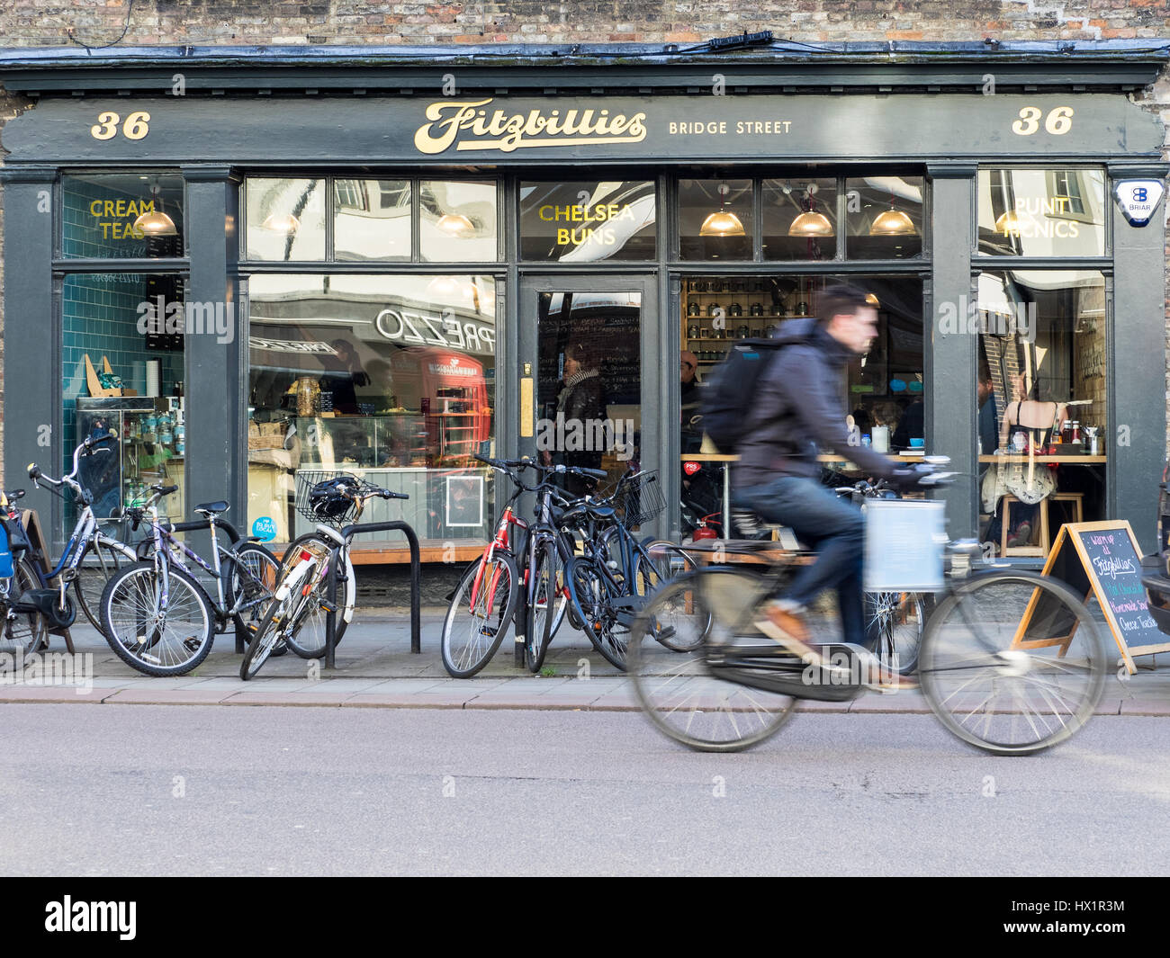Un ciclista pasa Fitzbillies Cambridges famosa cafetería/restaurante, famoso por su pegajoso bollos de Chelsea. Foto de stock