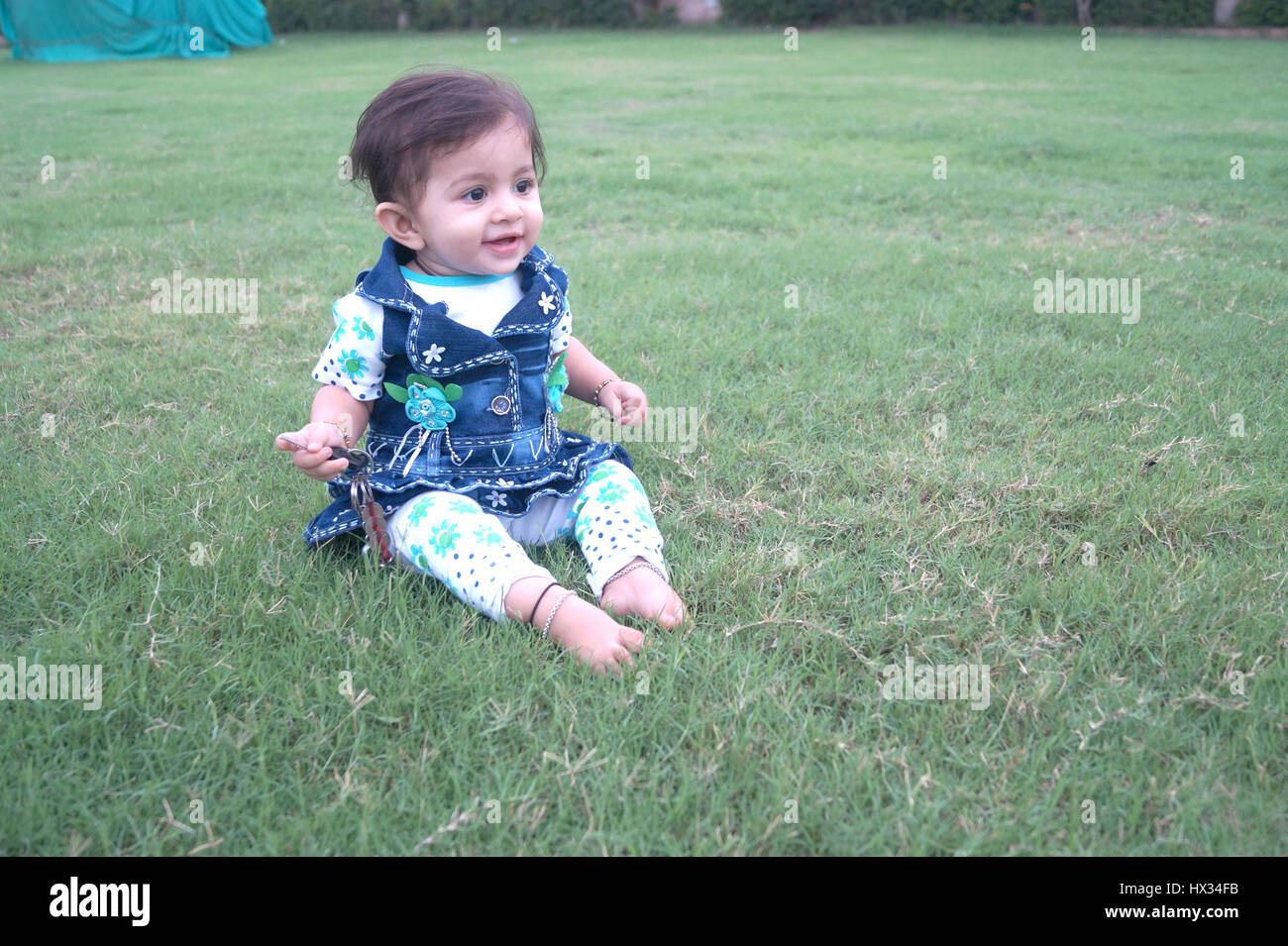 Lindo bebé indio pidiendo jugando en el jardín local en algún momento en la india Foto de stock