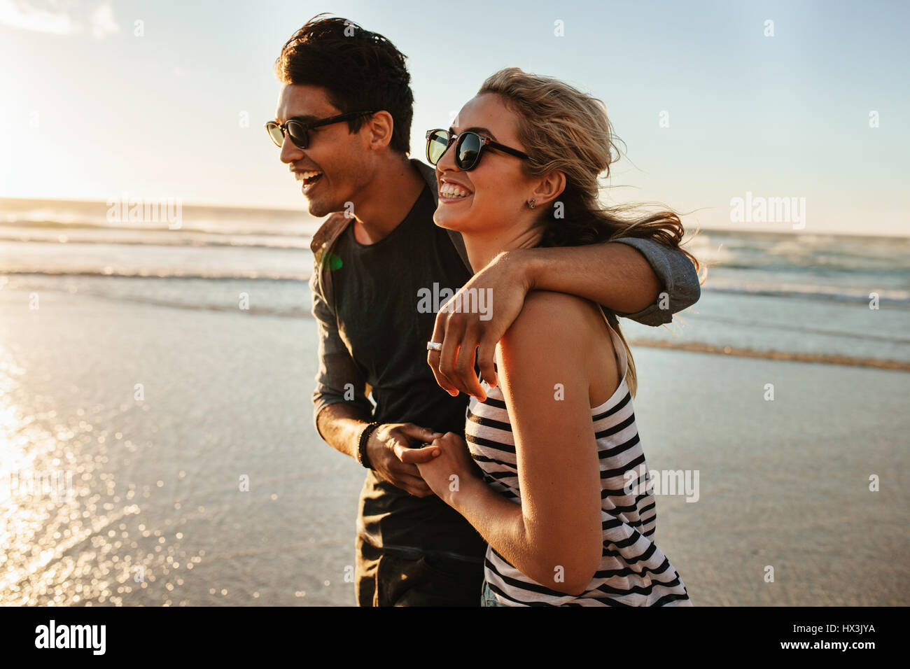 Disparó al aire libre de sonriente joven pareja caminando por la playa. Joven Hombre y Mujer paseando junto a la orilla del mar, en un día de verano. Foto de stock
