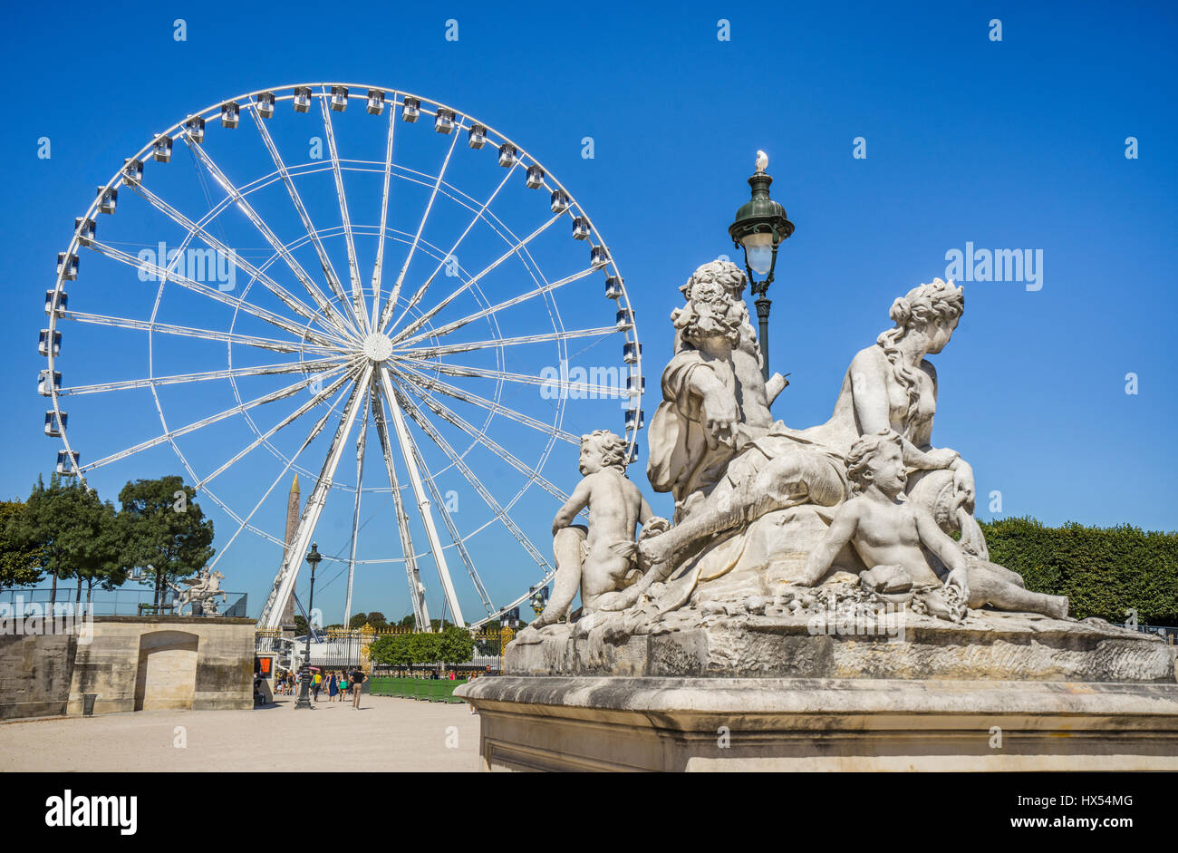 Francia, Paris, estatuas clásicas en los jardines de la Tullerías contra el telón de fondo de la gran rueda de Ferris carrusel Foto de stock