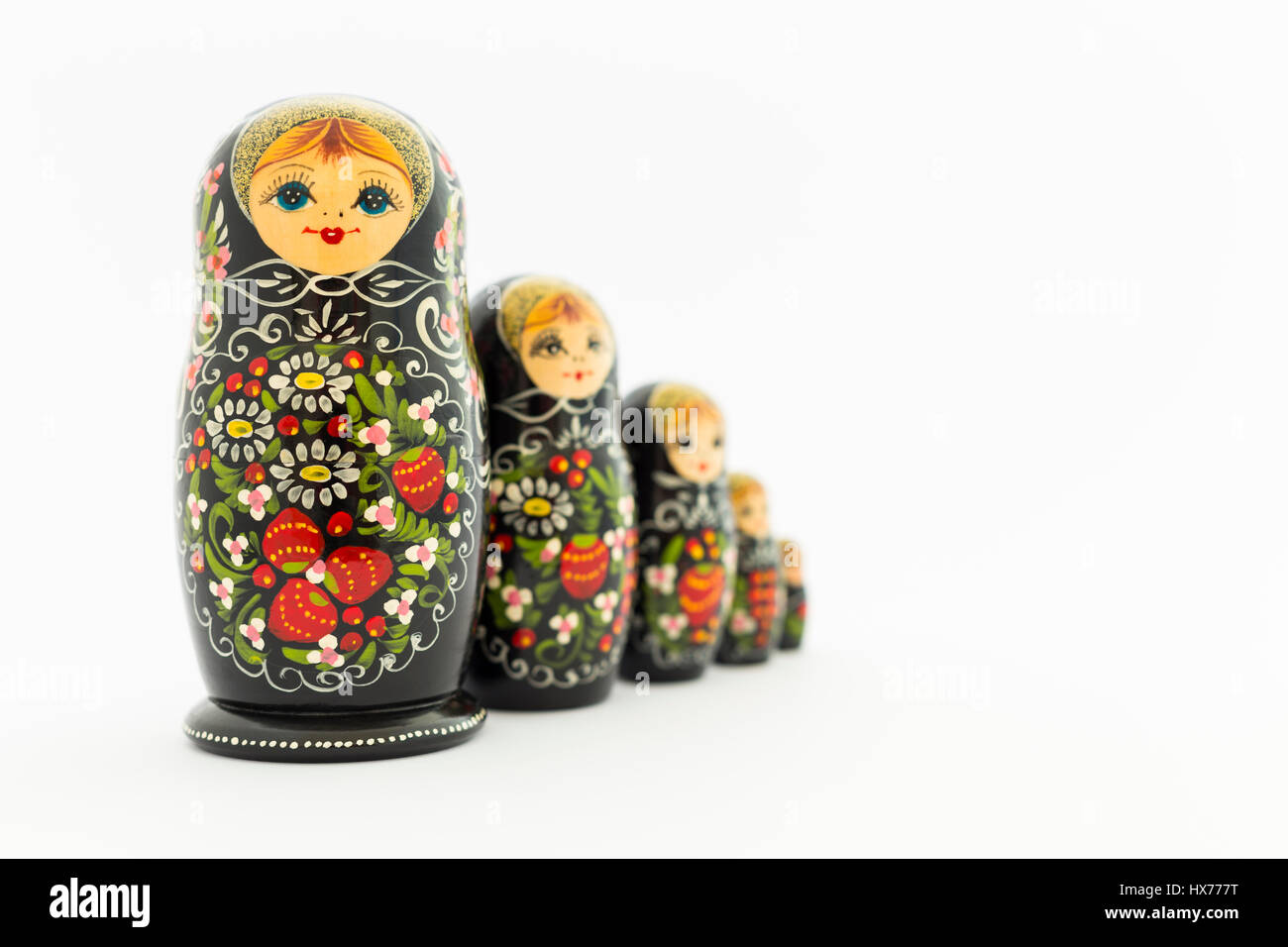 Hermosa negro matryoshka nesting rusa dolls (muñecas) con blanco, verde y rojo pintura delante de un fondo blanco Foto de stock