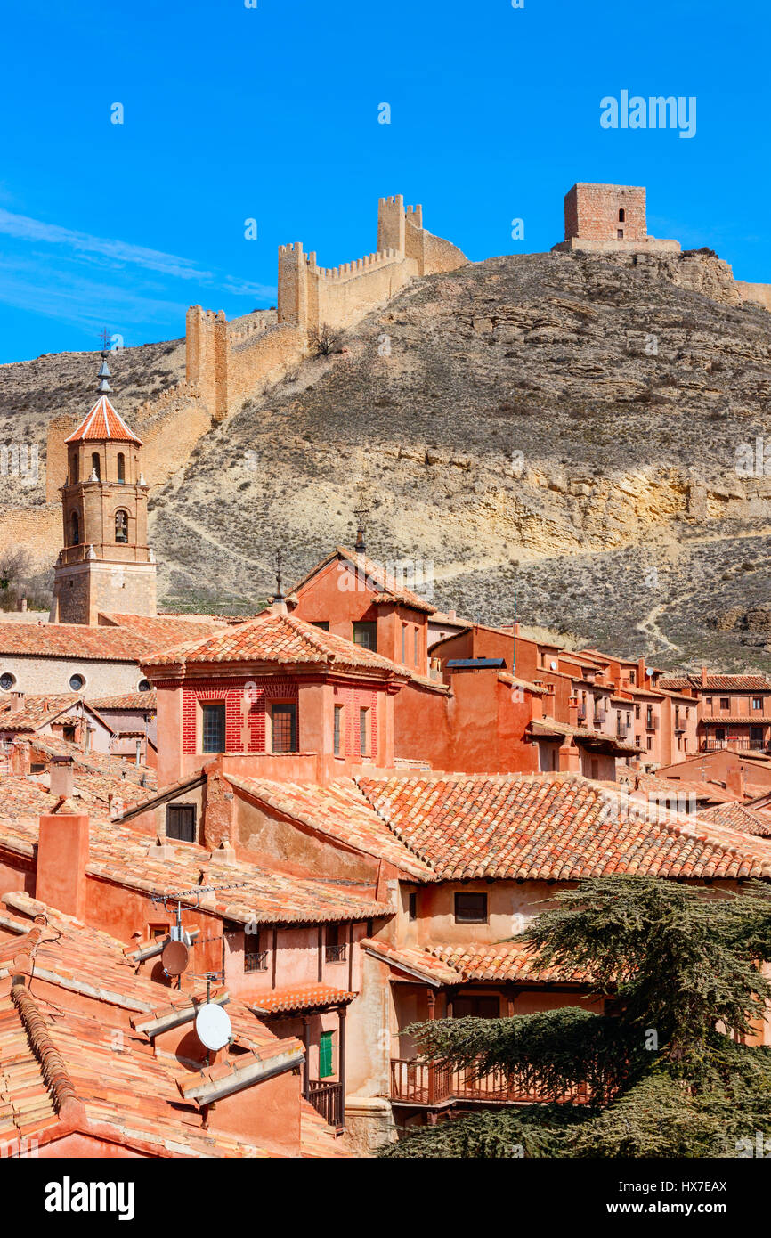 Las casas y las calles de Albarracín contra la ladera de la colina, con las murallas de la ciudad en la cima en un día soleado bajo un cielo azul. Teruel, España. Foto de stock