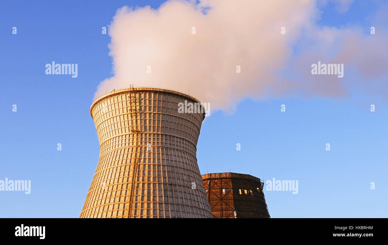 Torre de enfriamiento de agua pila humo sobre cielo azul Foto de stock