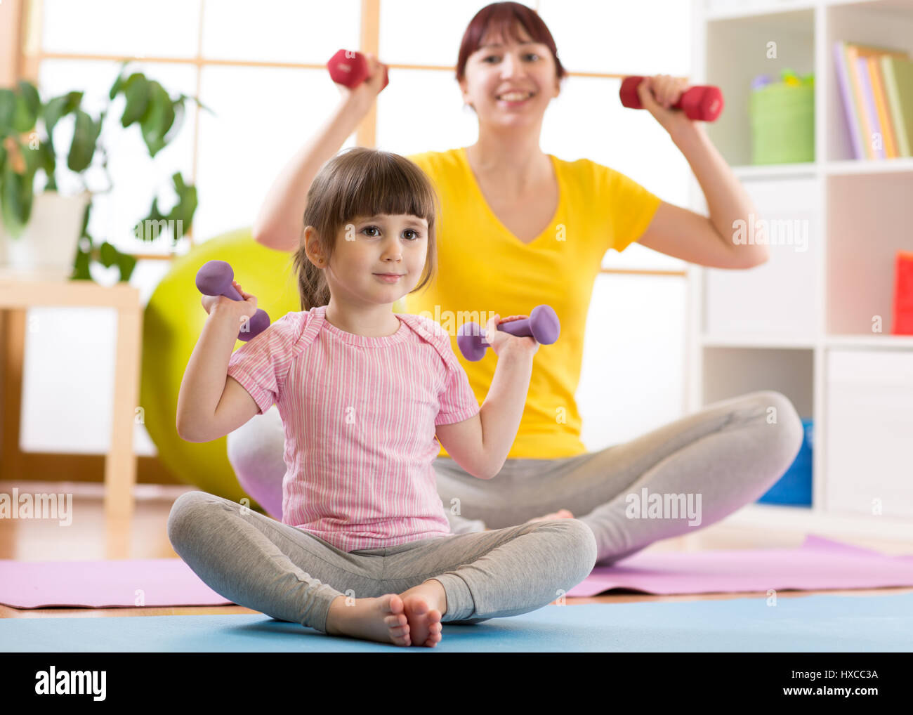 Mujer y a su hija kid haciendo ejercicios físicos con pesas Foto de stock