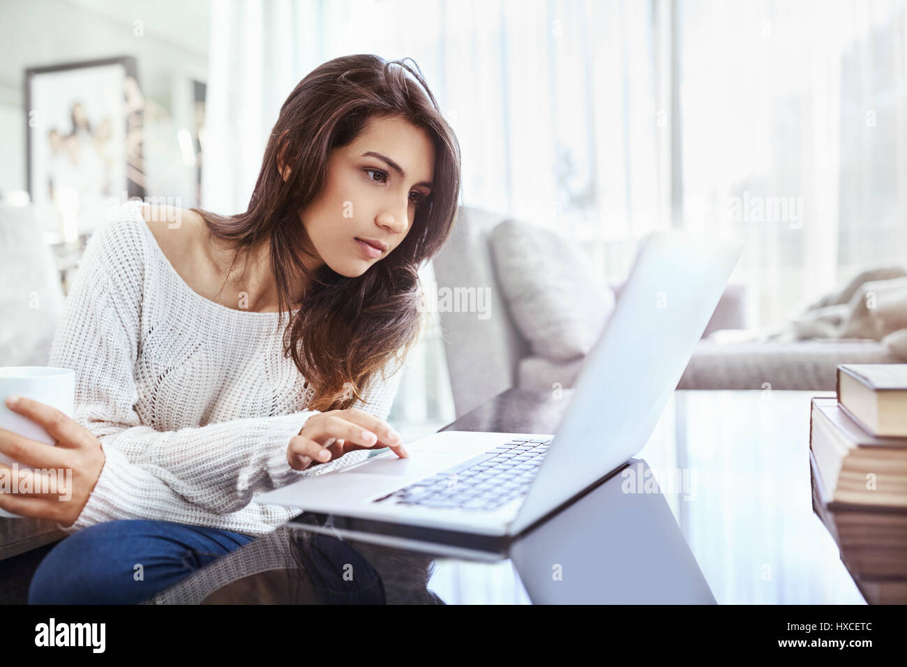 Mujer seria usando el portátil en la mesa de comedor Foto de stock