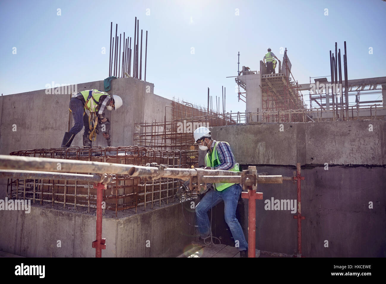 Los trabajadores de la construcción que trabajan en sunny sitio en construcción Foto de stock