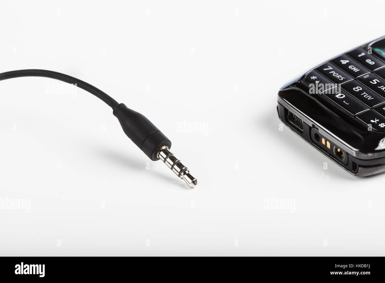 Accesorios de telefonía celular móvil, enchufe auriculares, conectores aislados un fondo blanco un negro teléfono con teclado Fotografía de stock - Alamy