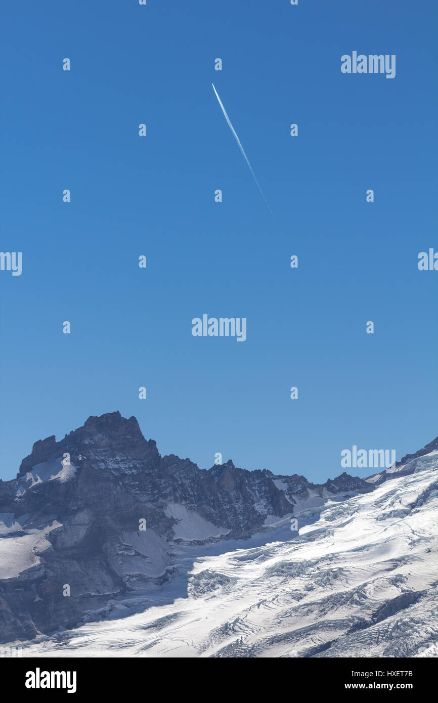 Plano blanco estelas de condensación streak diagonalmente a través de un cielo azul dentados, glaciares Ridge que conduce a Mount Rainier. Mt Fremont Lookout Trail, Monte Rai Foto de stock